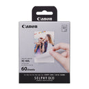 Canon photo paper packaging with a hand holding a printed photo on a white background
